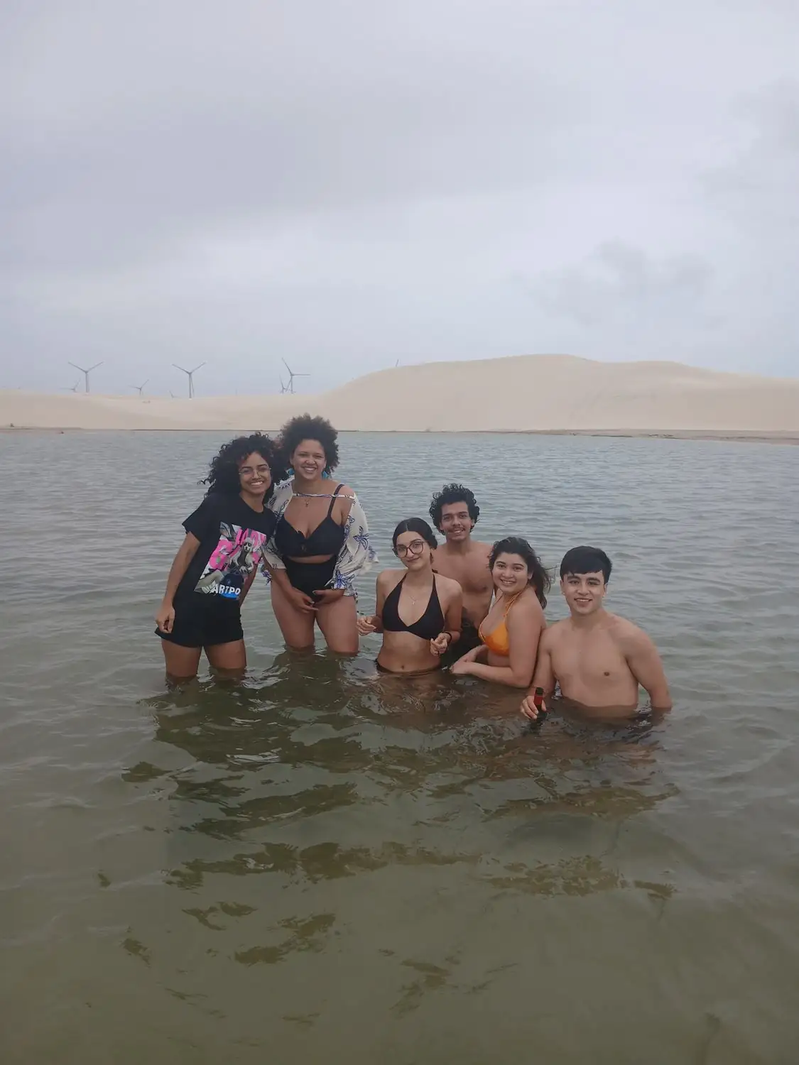 Moradores dentro da água de uma lagoa cercada por dunas