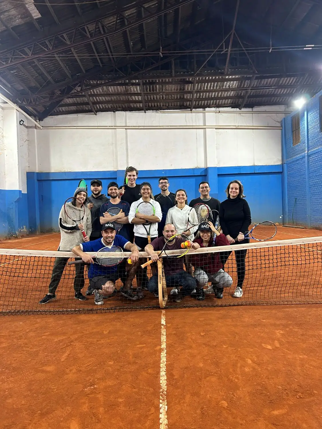 Grupo de moradores com raquetes na quadra de saibro