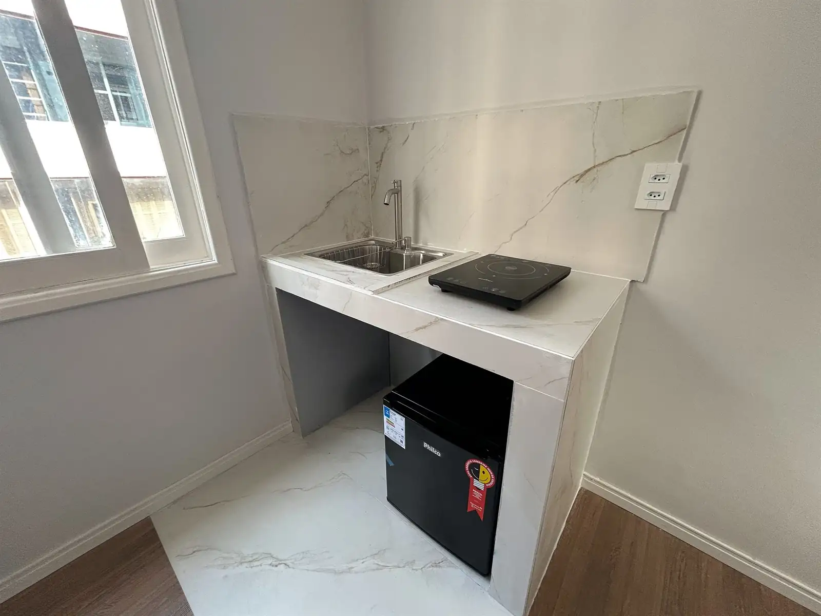 Bancada de cozinha do estúdio com pia, cooktop e frigobar embaixo